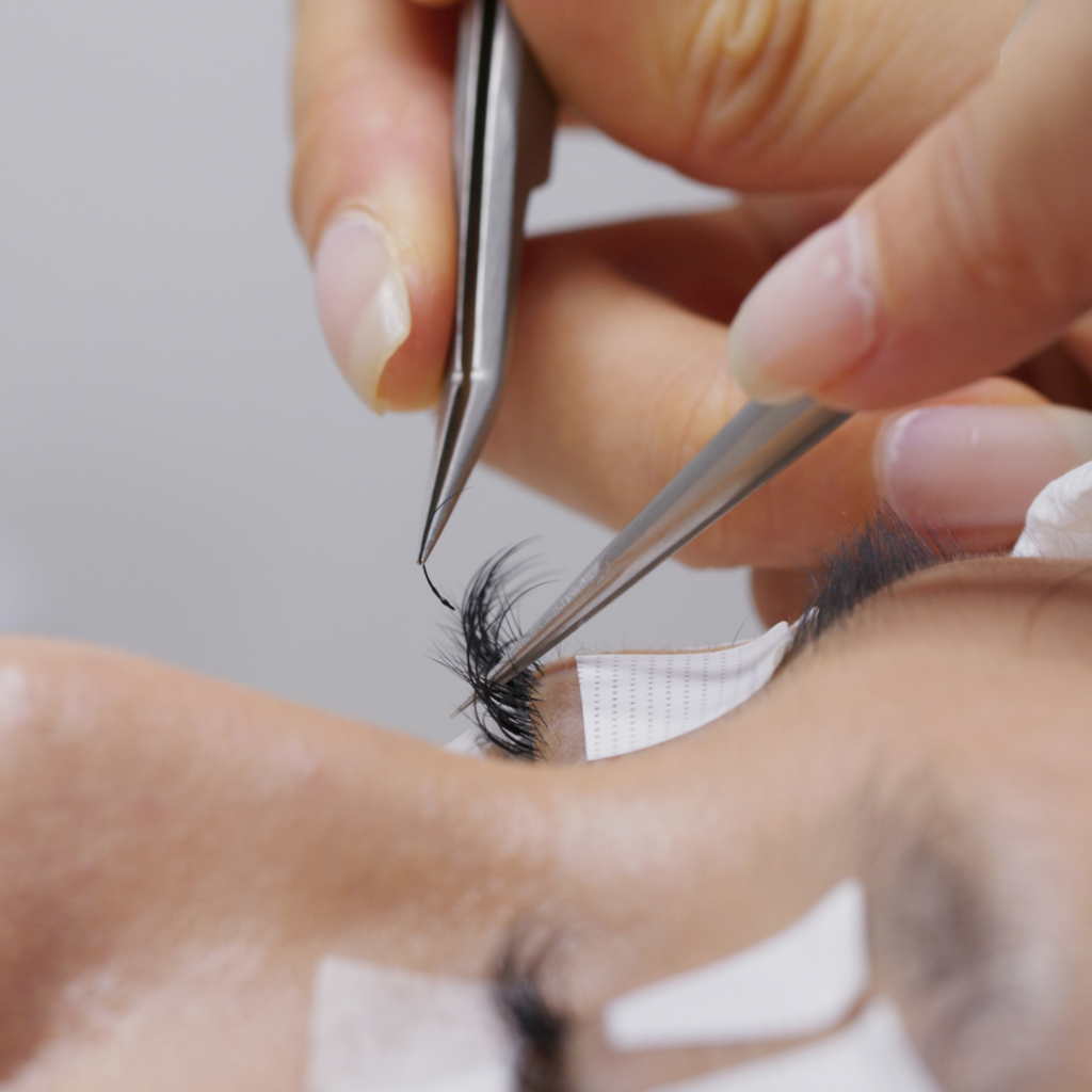 Nahaufnahme einer Pinzette beim Setzen von Lashextensions in der Beautylounge.