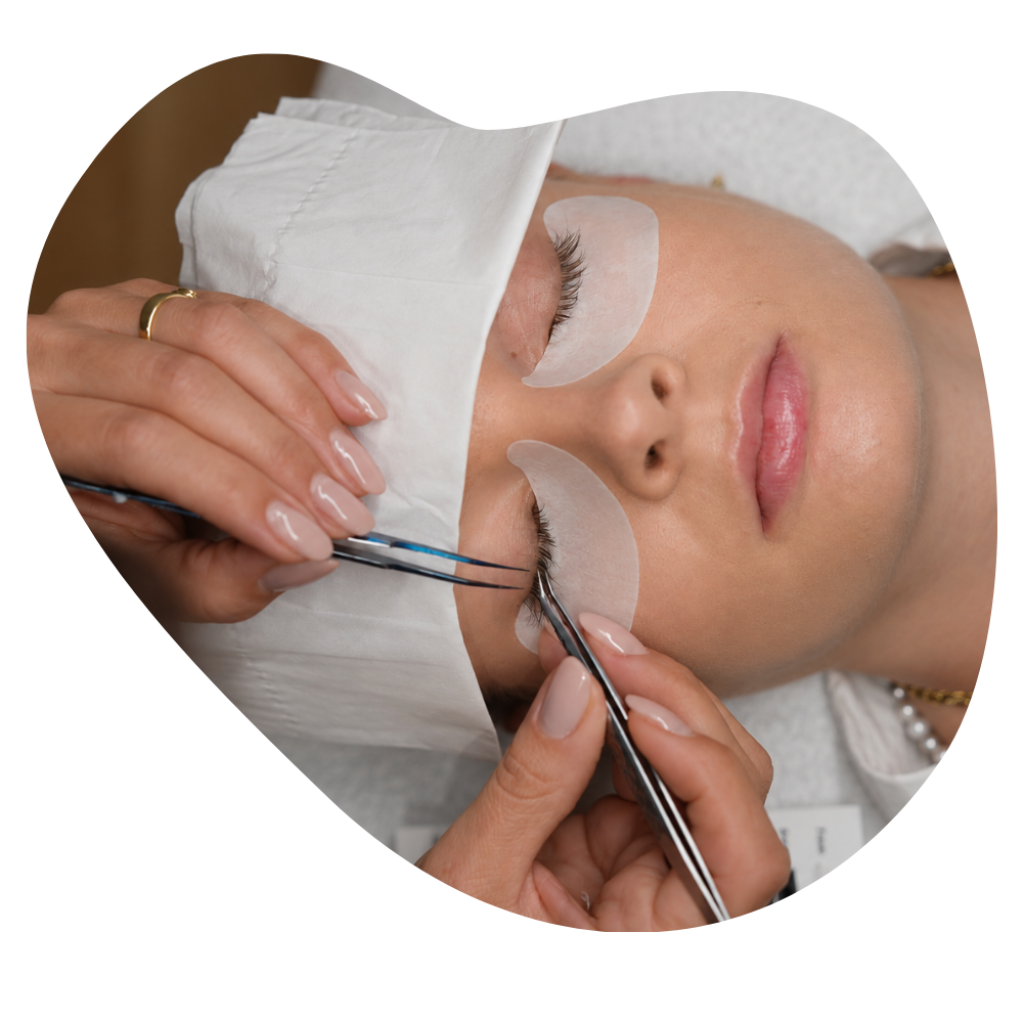Kosmetikerin setzt mit zwei Pinzetten Lashextensions auf die Naturwimpern einer Kundin mit Silikonpads.