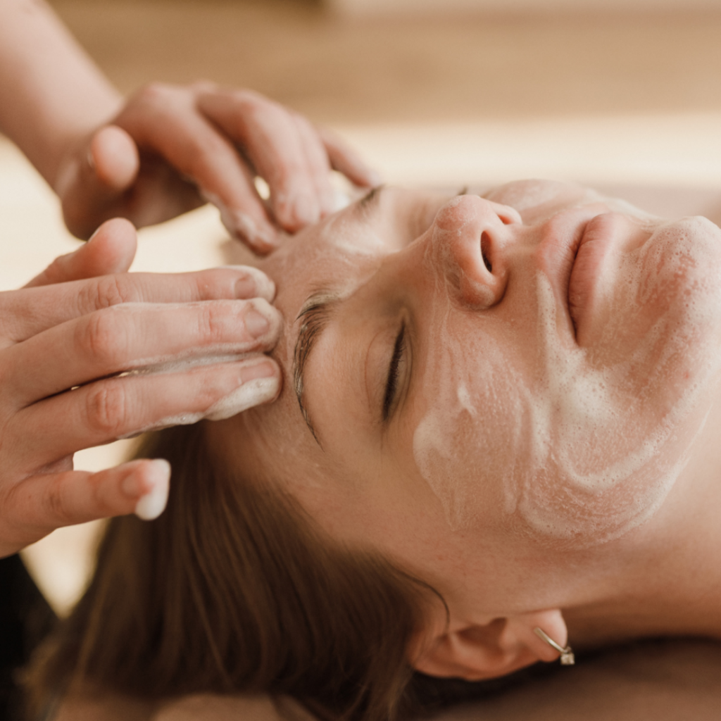 Kosmetikerin tr&auml;gt eine weisse Gesichtsmaske auf, Gesichtsbehandlung in der Beautylounge Basel.