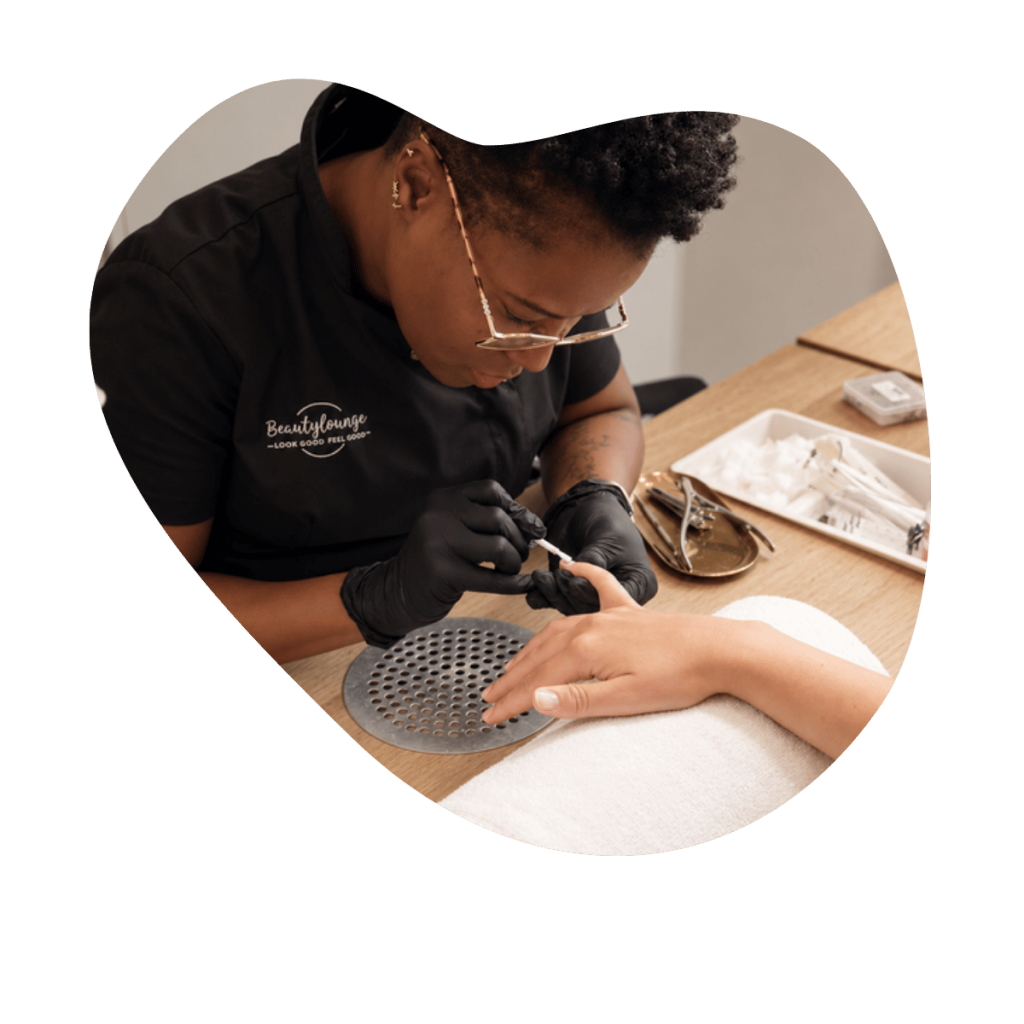 Nagelstylistin der Beautylounge Basel tr&auml;gt CND Shellac mit feinem Pinsel auf die N&auml;gel einer Kundin auf.