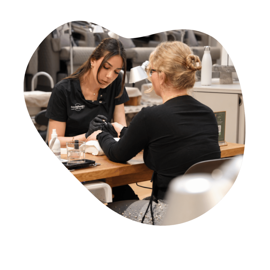 Manicure in der Beautylounge Basel mit Cuccio Produkten, Kosmetikerin pflegt die H&auml;nde einer Kundin am Behandlungstisch.