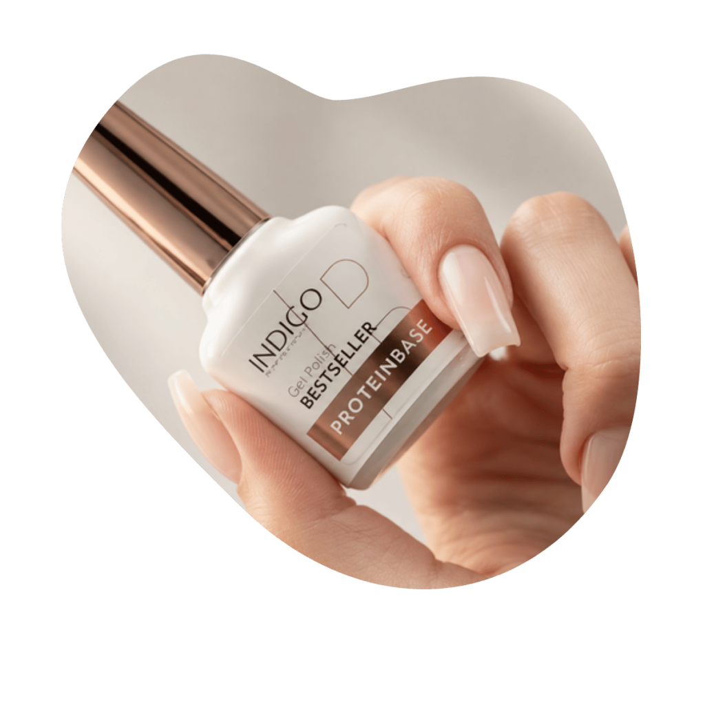 Hand h&auml;lt Indigo Nails Protein Base Flasche mit ros&eacute;goldenem Deckel, nat&uuml;rliche N&auml;gel im Nude Look, Beautylounge Basel.