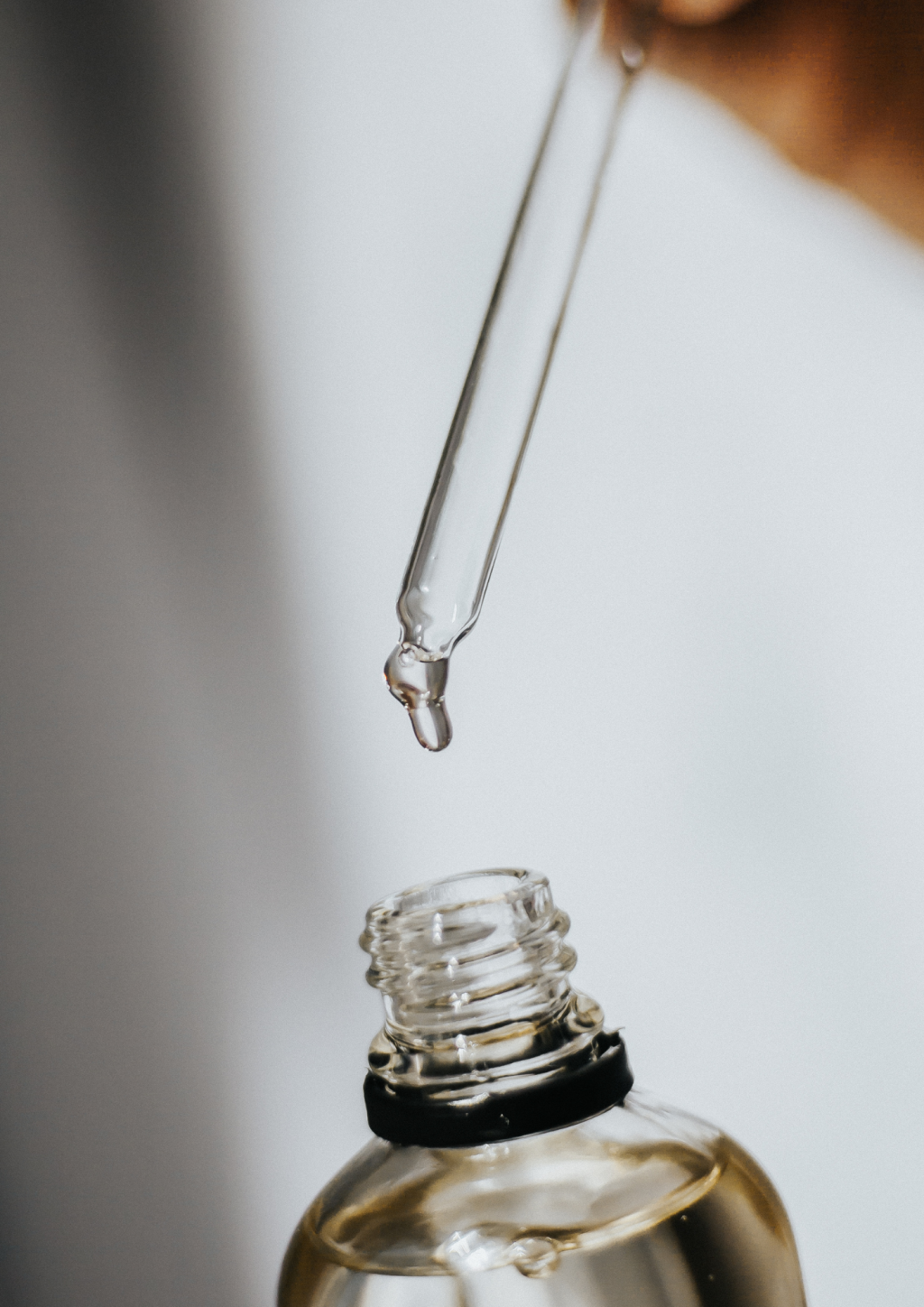 Pipette &uuml;ber einer Serumflasche, Wirkstoffpflege f&uuml;r Gesichtsbehandlungen in der Beautylounge.