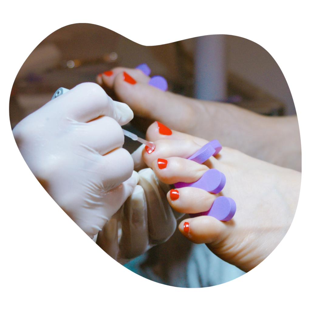 Zehenn&auml;gel werden bei einer Business Pedicure rot lackiert, Zehenspreizer sch&uuml;tzen die Haut.